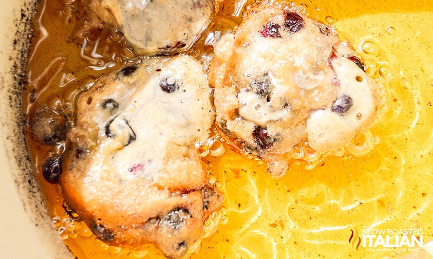 frying blueberry fritters in a pot of oil