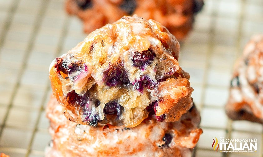 closeup of stacked blueberry fritters covered in glaze