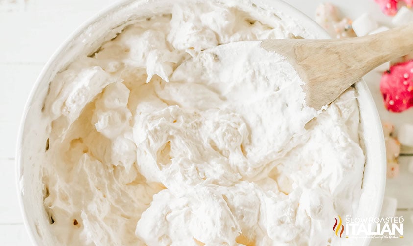 mixing circus cookie fluff salad with a wooden spoon