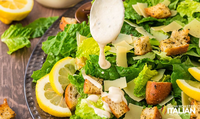 adding homemade dressing to classic caesar salad