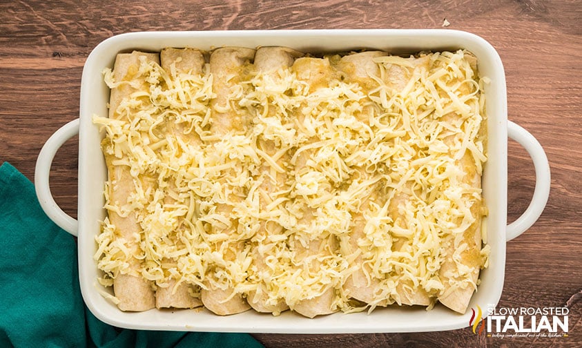 salsa verde chicken enchiladas in a 9x13 baking dish covered with shredded cheese