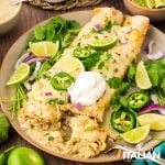 salsa verde chicken enchiladas on a plate with slice jalapenos and sliced limes