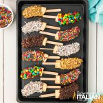 sheet pan of frozen chocolate covered bananas with toppings