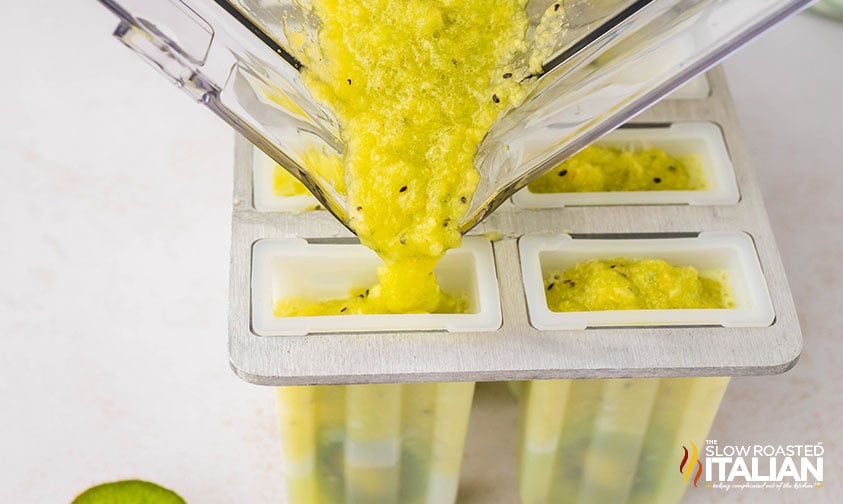 pouring kiwi popsicles mixture into a popsicle mold