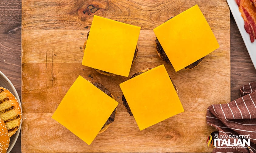 adding sliced cheese to bbq bacon burger patties