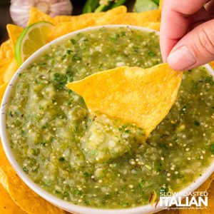 closeup of dipping a tortilla chip in roasted salsa verde