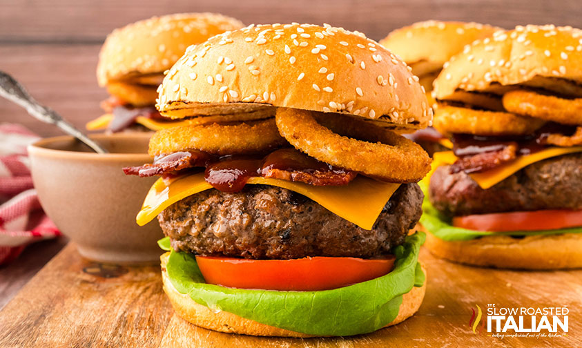 rodeo cowboy burgers loaded with onion rings, bacon, cheese, lettuce, tomatoes and barbecue sauce on a toasted bun