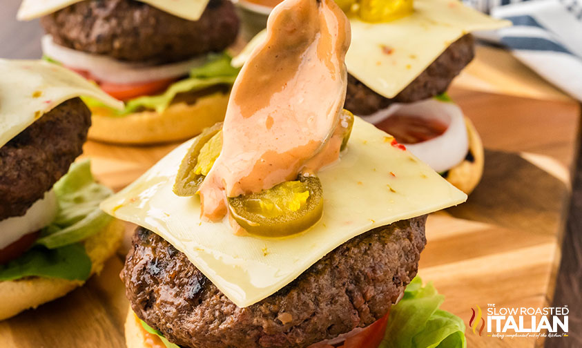 spreading spicy barbecue ranch sauce on top of jalapeno burger