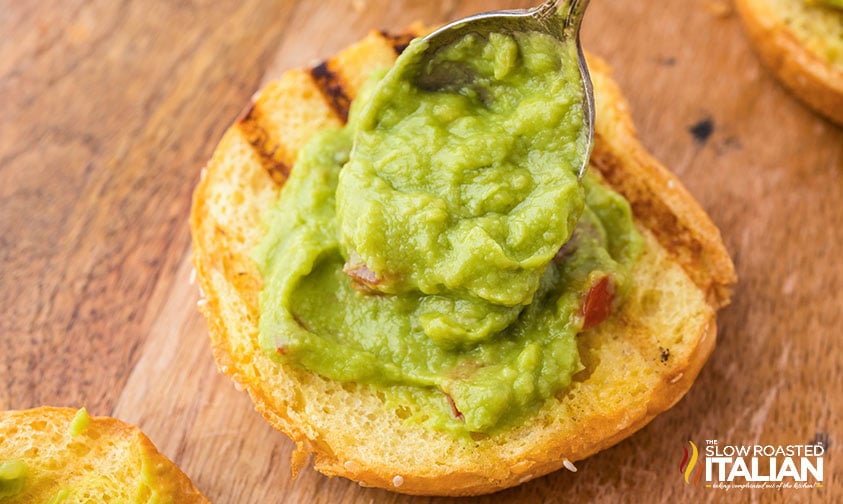 spreading guacamole on a bun