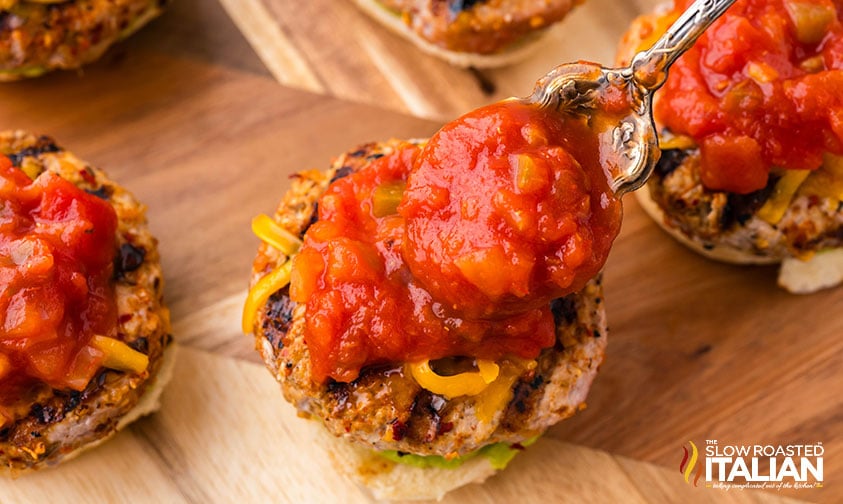 spooning salsa on top of turkey burger sliders