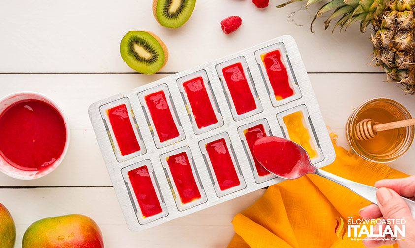 layering pureed fruit in a mold to make tropical popsicles