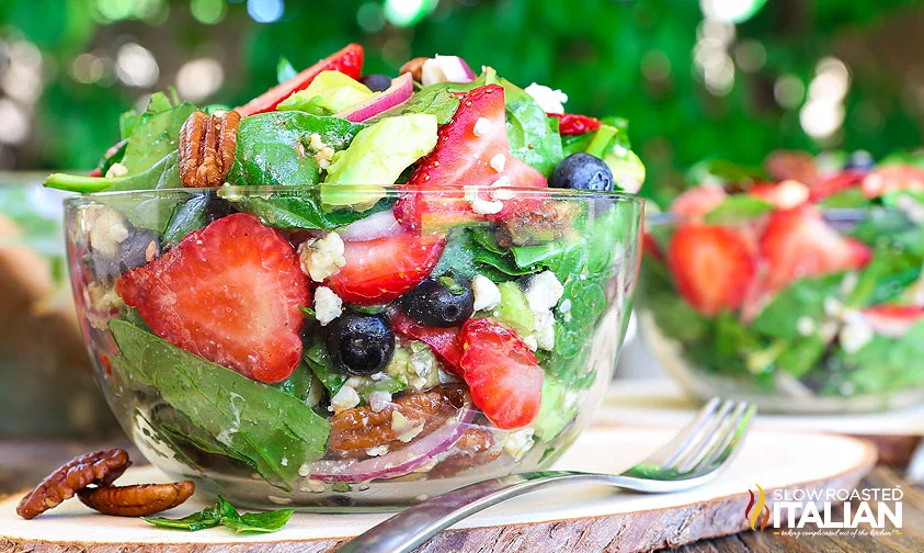 clear bowl of strawberry spinach salad with blue cheese