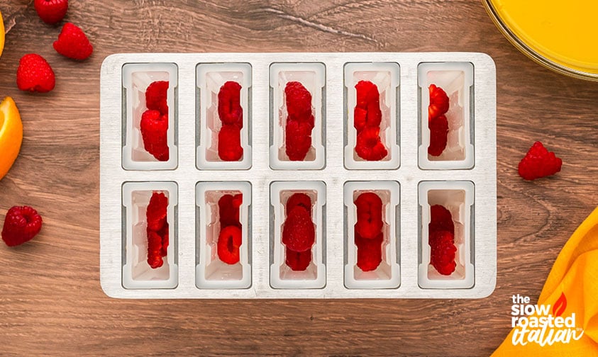 adding fresh raspberries to popsicle mold