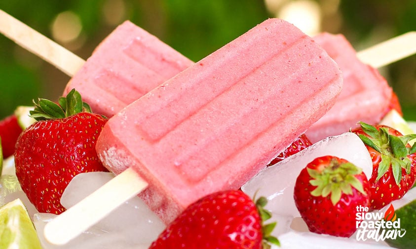 closeup of strawberry yogurt popsicles on ice with fresh strawberries