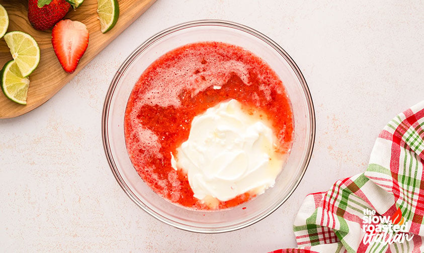 strawberry puree mixed with yogurt in a mixing bowl
