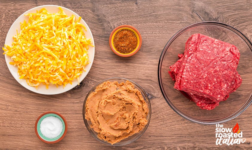 Ingredients for refried bean casserole including ground beef, refried beans, shredded cheese, taco seasoning, and salt