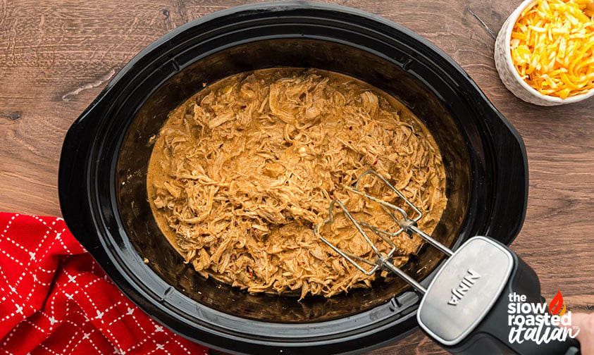 Shredding chicken with a hand mixer in the slow cooker to make crockpot Mexican chicken