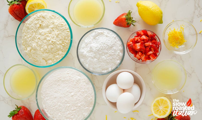 Ingredients for strawberry brownies including flour, sugar, eggs, diced strawberries, lemon juice, and lemon zest