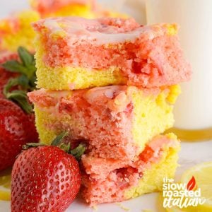 Stacked strawberry brownies with a pink and yellow lemonade swirl and white lemon glaze, garnished with fresh strawberries and lemon slices