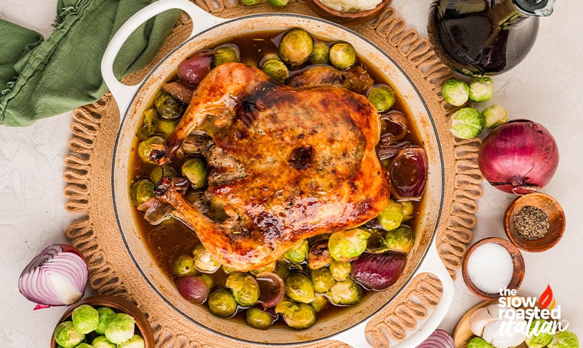 Roast chicken recipe in a pot with Brussels sprouts and red onion, surrounded by fresh ingredients including onion, pepper, and balsamic vinegar