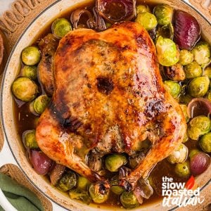 Roast chicken recipe with golden crispy skin, served in a pan with roasted Brussels sprouts and shallots in pan drippings