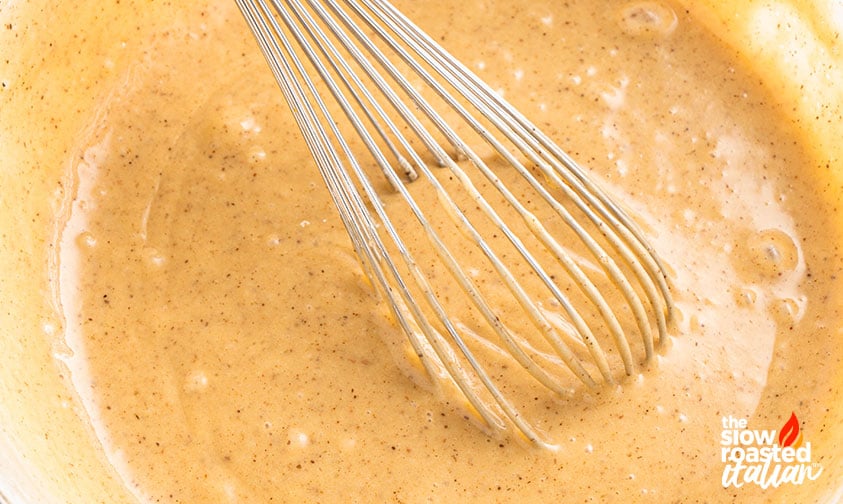 Close-up of a whisk mixing apple bread batter in a bowl