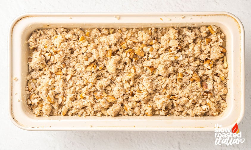 Overhead view of unbaked apple bread batter topped with pecan streusel in a loaf pan
