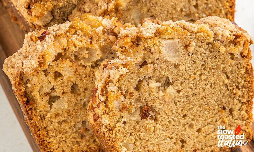 Close-up of sliced apple bread with visible apple chunks and a crumbly pecan streusel topping