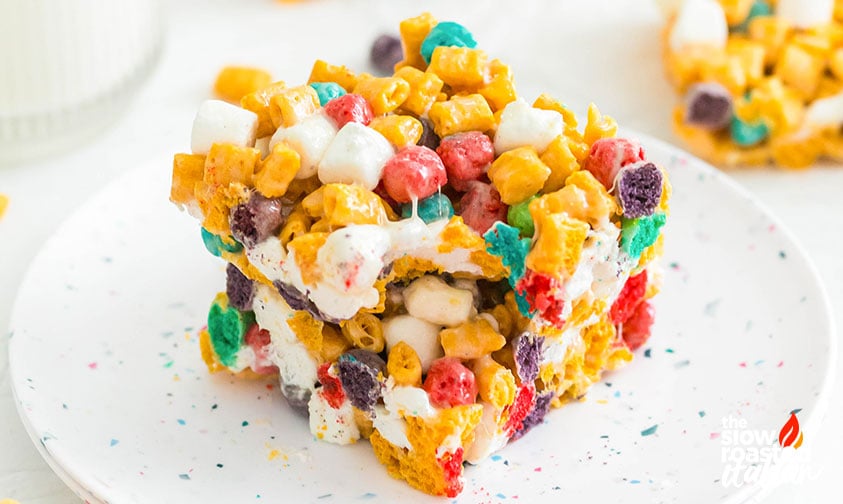 Close-up of a Cap’n Crunch cereal bar with a bite taken out, showing colorful cereal and marshmallows on a speckled plate