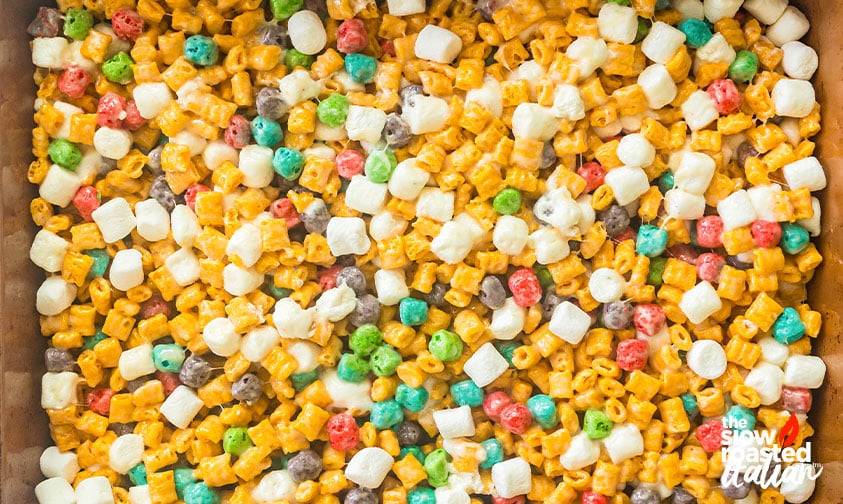 Overhead view of Cap’n Crunch cereal bar mixture pressed into a pan, studded with mini marshmallows