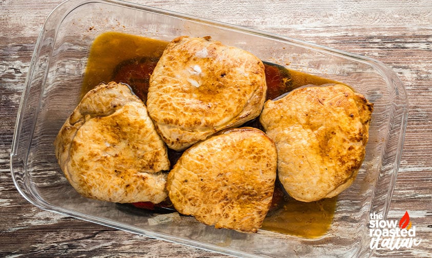 Baked marinated pork chops in a glass baking dish with pan juices