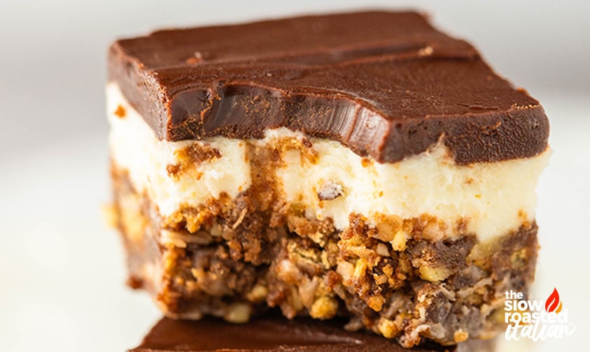 Close-up of a single Nanaimo bar showing the chocolate top, creamy middle, and crumbly nut and oat crust layers
