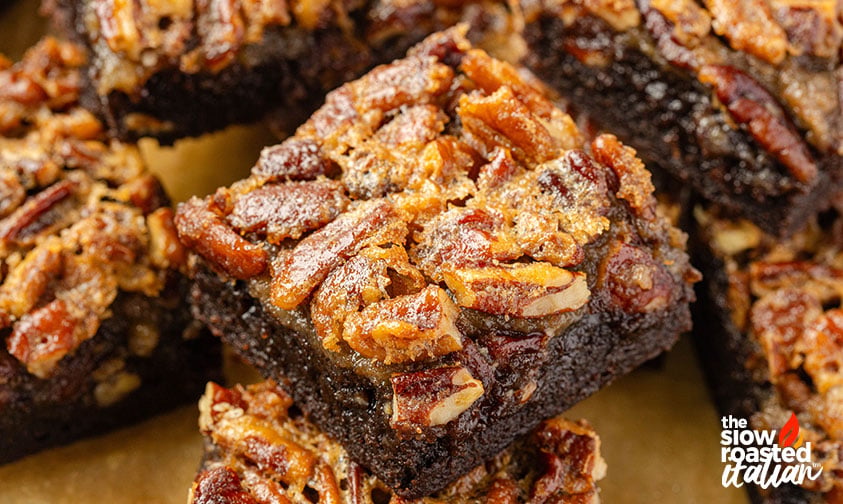 Close-up of stacked pecan pie brownies topped with a gooey, caramelized pecan layer