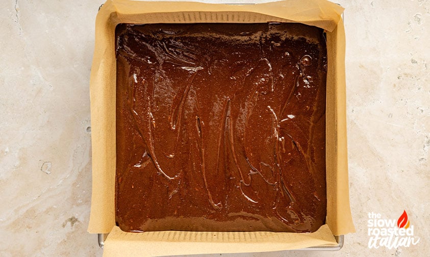 Process: brownie batter spread in a parchment-lined 9x9 pan
