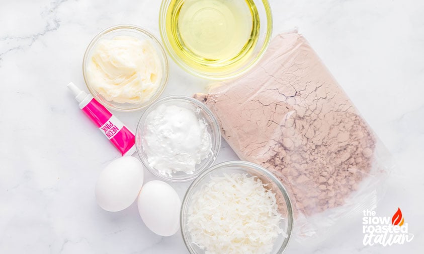 Ingredients for coconut brownies including brownie mix, oil, eggs, shredded coconut, marshmallow fluff, and pink food coloring